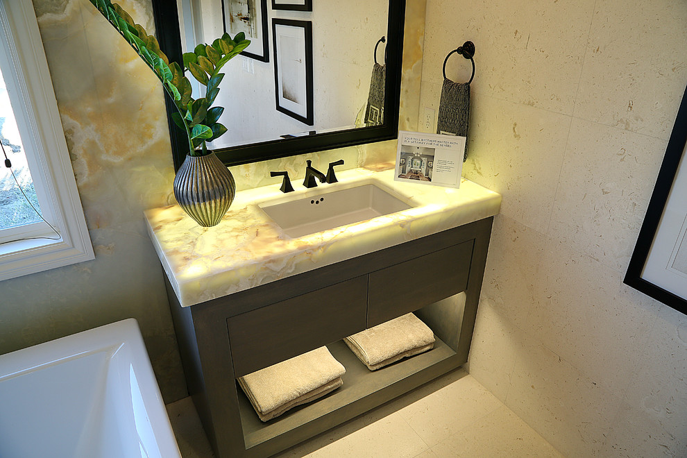 Inredning av ett modernt mellanstort beige beige badrum med dusch, med öppna hyllor, grå skåp, ett fristående badkar, beige kakel, cementkakel, beige väggar, cementgolv, ett undermonterad handfat, bänkskiva i onyx och beiget golv