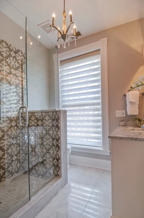 Mid-sized transitional 3/4 white tile porcelain tile and gray floor alcove shower photo in Chicago with raised-panel cabinets, white cabinets, gray walls, an undermount sink, marble countertops and a hinged shower door