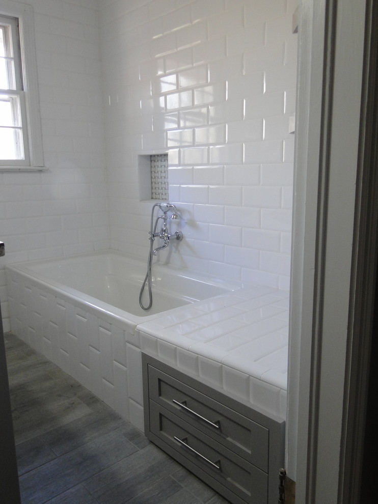 Стильный дизайн: ванная комната в стиле неоклассика (современная классика) с фасадами в стиле шейкер, серыми фасадами, накладной ванной, душем над ванной, унитазом-моноблоком, белой плиткой, керамической плиткой, белыми стенами, полом из винила, душевой кабиной, врезной раковиной и столешницей из плитки - последний тренд