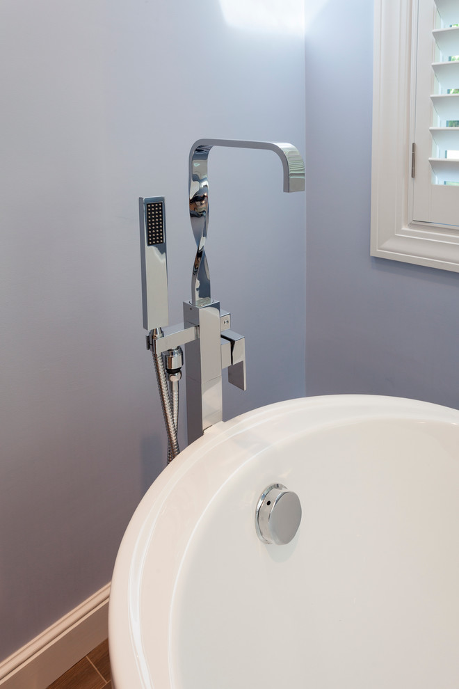 Cette image montre une salle de bain principale design avec une baignoire indépendante et un mur bleu.