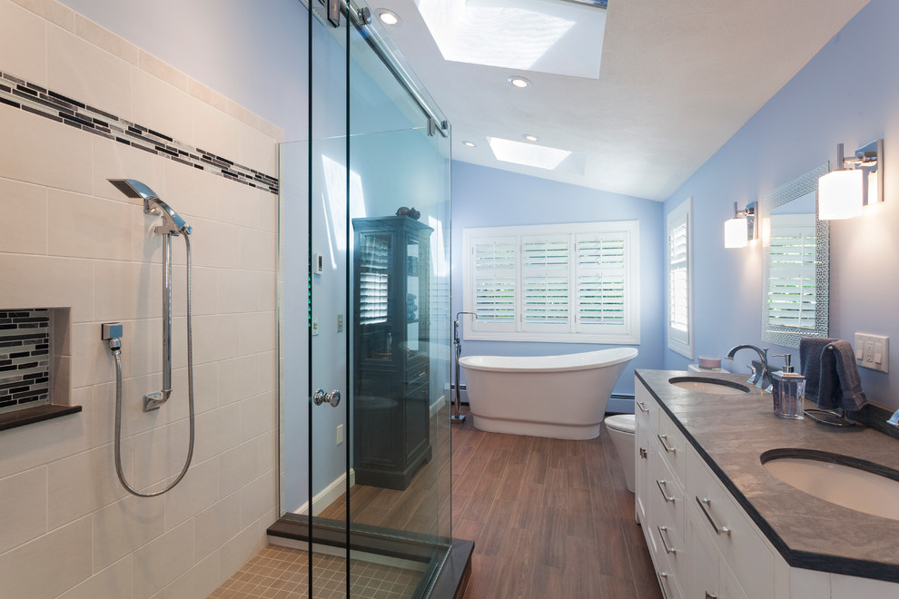 Modern inredning av ett en-suite badrum, med ett undermonterad handfat, ett fristående badkar, en hörndusch, vit kakel, keramikplattor och blå väggar