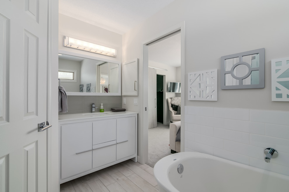 Mittelgroßes Modernes Duschbad mit Unterbauwaschbecken, weißen Schränken, freistehender Badewanne, Eckdusche, Wandtoilette mit Spülkasten und weißer Wandfarbe in Calgary