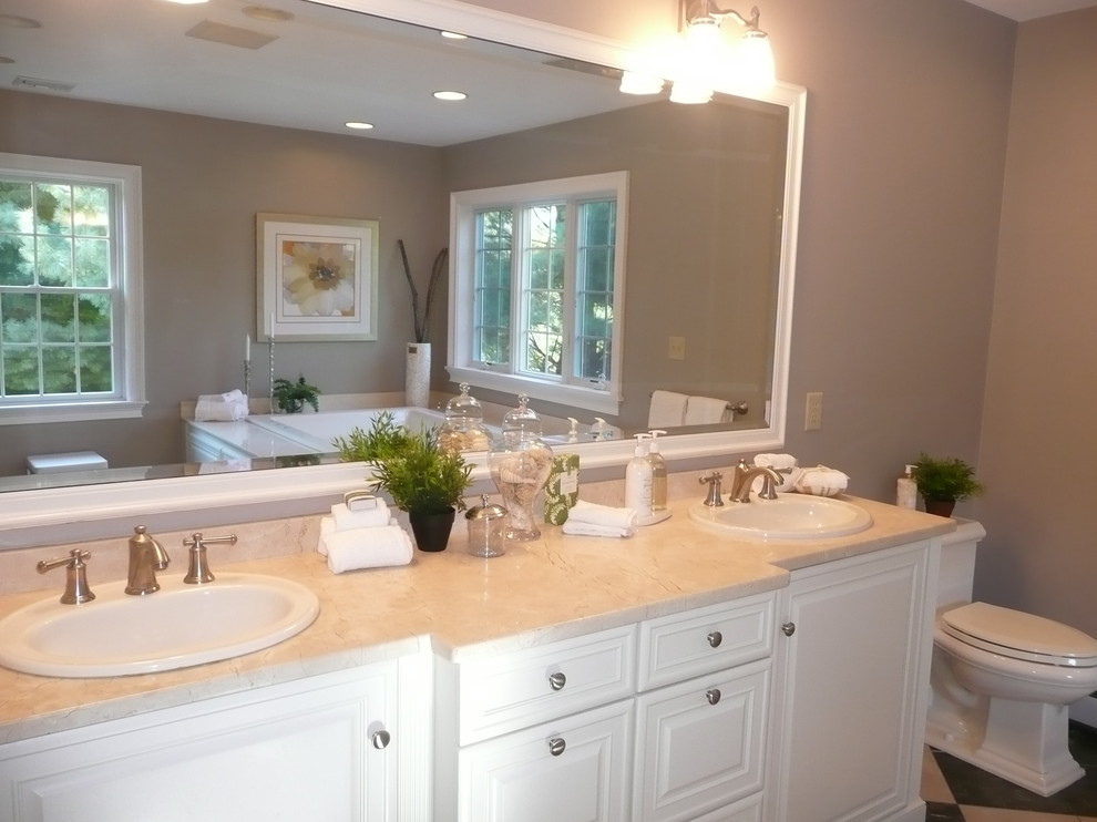 Large traditional ensuite bathroom in Boston with a built-in sink, raised-panel cabinets, white cabinets, granite worktops, a built-in bath, a one-piece toilet, multi-coloured tiles, ceramic tiles, grey walls and ceramic flooring.
