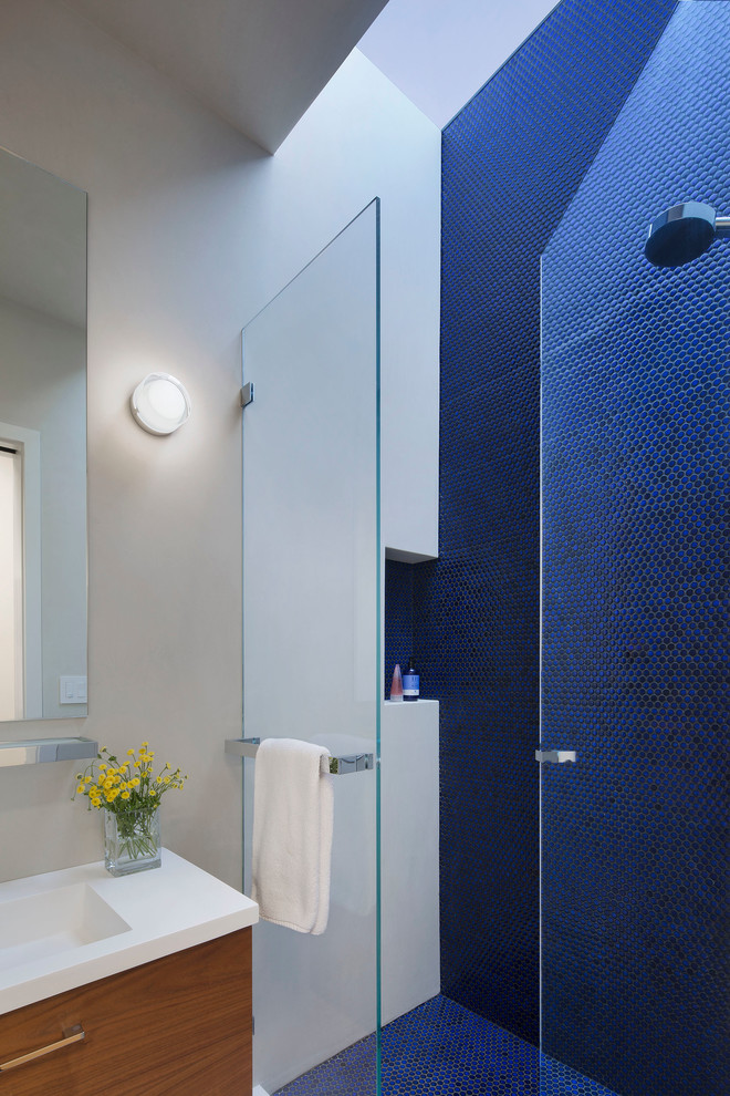 Imagen de cuarto de baño contemporáneo pequeño con armarios con paneles lisos, puertas de armario de madera oscura, ducha empotrada, baldosas y/o azulejos azules, baldosas y/o azulejos en mosaico, paredes blancas, aseo y ducha, lavabo integrado y encimera de acrílico