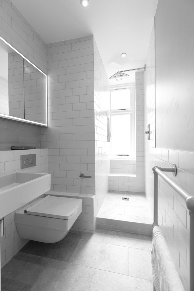 Idéer för att renovera ett litet funkis vit vitt badrum med dusch, med en öppen dusch, en vägghängd toalettstol, vit kakel, keramikplattor, vita väggar, klinkergolv i porslin, ett väggmonterat handfat, kaklad bänkskiva, grått golv och med dusch som är öppen