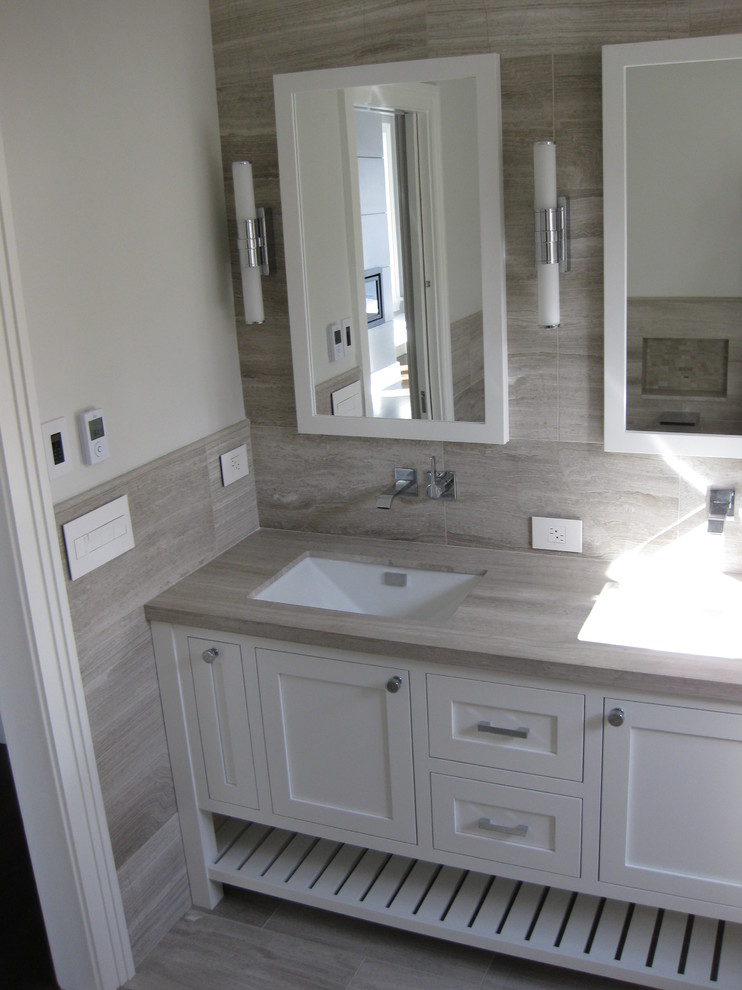 Idéer för att renovera ett mellanstort funkis en-suite badrum, med ett undermonterad handfat, skåp i shakerstil, vita skåp, granitbänkskiva, ett undermonterat badkar, en vägghängd toalettstol, grå kakel, porslinskakel, grå väggar och klinkergolv i porslin