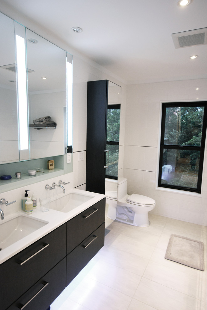 Ejemplo de cuarto de baño contemporáneo con lavabo bajoencimera, puertas de armario negras, bañera encastrada sin remate, baldosas y/o azulejos blancos, baldosas y/o azulejos de cemento y paredes blancas