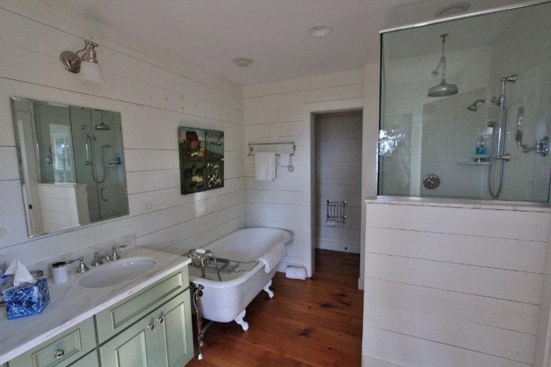 Klassisches Badezimmer mit Schrankfronten mit vertiefter Füllung, grünen Schränken, Löwenfuß-Badewanne, weißer Wandfarbe, braunem Holzboden und Unterbauwaschbecken in Burlington