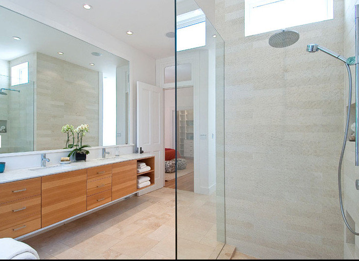This is an example of a large modern ensuite bathroom in San Francisco with flat-panel cabinets, light wood cabinets, a freestanding bath, a walk-in shower, a one-piece toilet, beige tiles, porcelain tiles, white walls, ceramic flooring, a submerged sink and marble worktops.