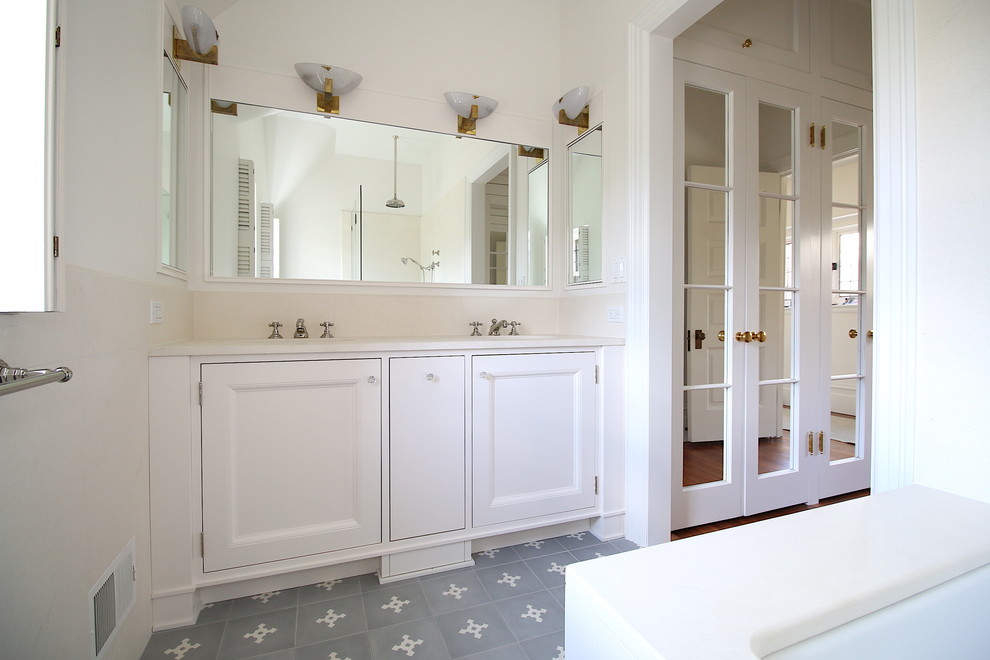 Cette photo montre une salle de bain chic de taille moyenne avec une baignoire encastrée, un carrelage blanc, du carrelage en pierre calcaire, un mur blanc, carreaux de ciment au sol, un lavabo encastré et un sol gris.