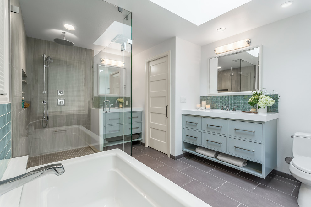 Design ideas for a traditional ensuite bathroom in Seattle with flat-panel cabinets, grey cabinets, a freestanding bath, a double shower, a one-piece toilet, grey tiles, glass tiles, white walls, porcelain flooring, a submerged sink and engineered stone worktops.