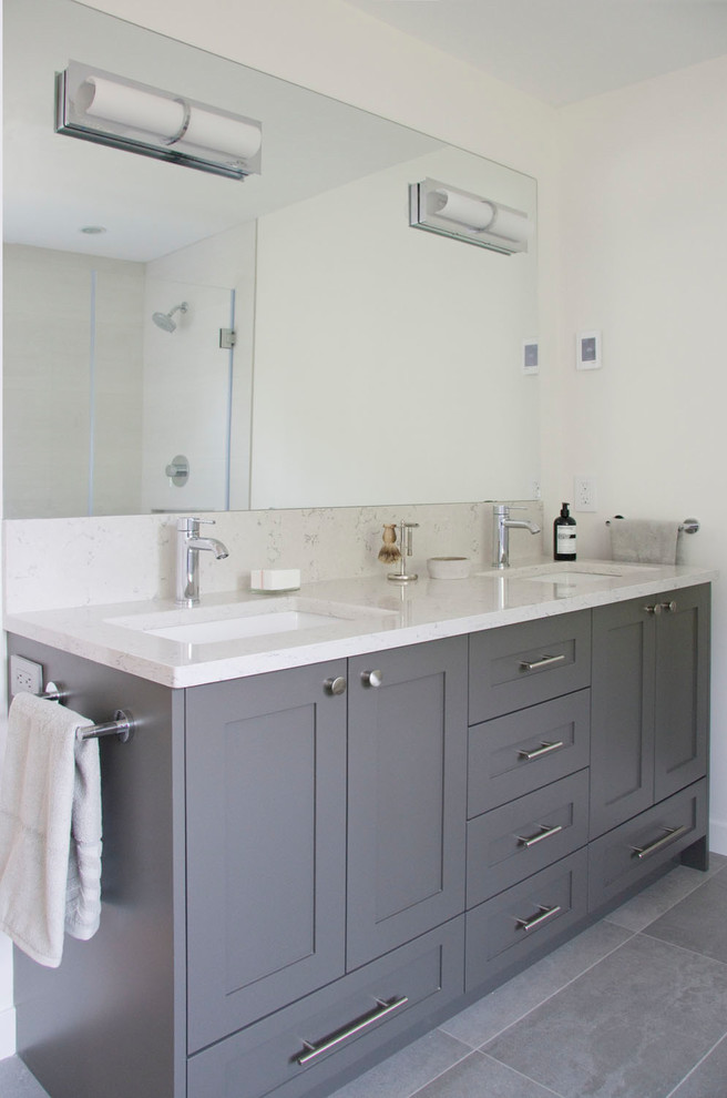 Photo of a large contemporary ensuite bathroom in Vancouver with shaker cabinets, grey cabinets, a submerged bath, a corner shower, a one-piece toilet, white tiles, ceramic tiles, white walls, porcelain flooring, a submerged sink, engineered stone worktops, grey floors and a hinged door.