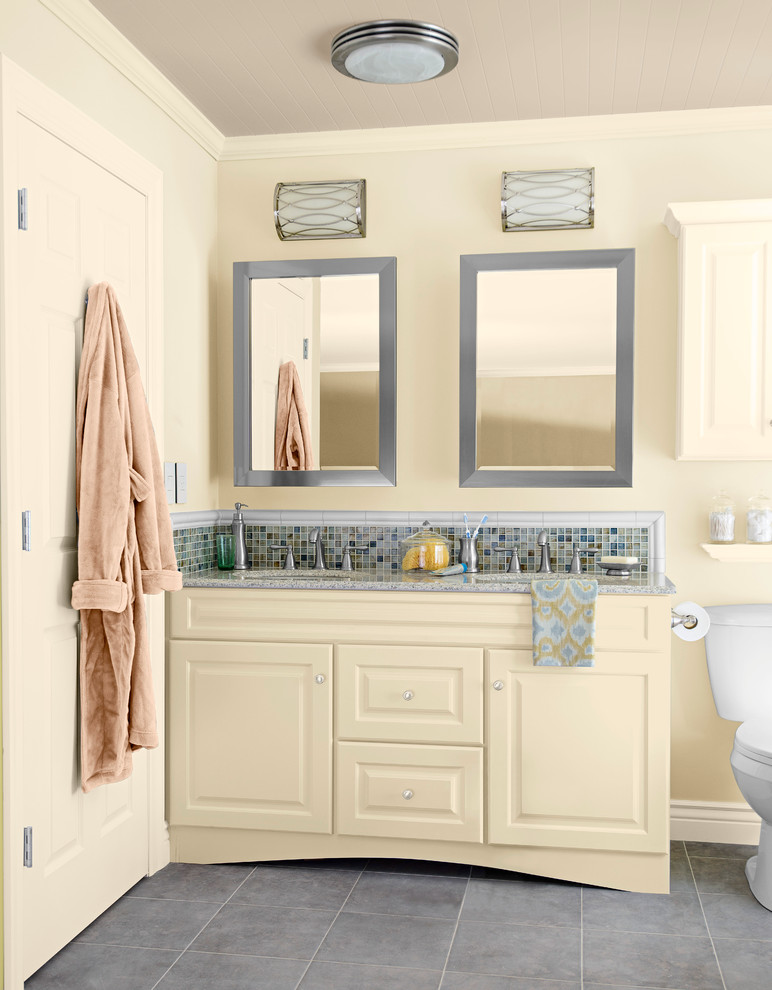 На фото: главная ванная комната среднего размера в стиле неоклассика (современная классика) с врезной раковиной, фасадами с выступающей филенкой, желтыми фасадами, столешницей из гранита, раздельным унитазом, разноцветной плиткой, плиткой мозаикой, желтыми стенами и полом из керамической плитки