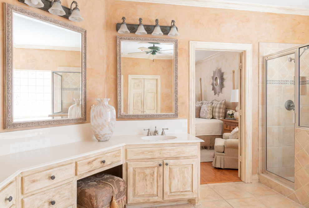 Inspiration for a mid-sized timeless master beige tile and porcelain tile porcelain tile and beige floor corner shower remodel in Dallas with raised-panel cabinets, distressed cabinets, a two-piece toilet, beige walls, an undermount sink, solid surface countertops, a hinged shower door and white countertops