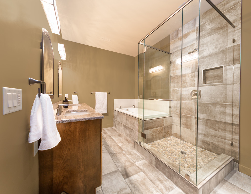 Photo of a medium sized contemporary ensuite bathroom in Vancouver with granite worktops, flat-panel cabinets, medium wood cabinets, a built-in bath, an alcove shower, beige tiles, ceramic tiles, ceramic flooring, a submerged sink, beige walls and a two-piece toilet.