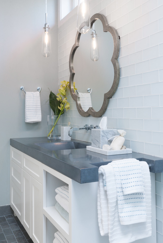 Immagine di una stanza da bagno minimal con lavabo integrato, consolle stile comò, ante bianche, top in cemento, doccia a filo pavimento, WC monopezzo, piastrelle blu e piastrelle di vetro
