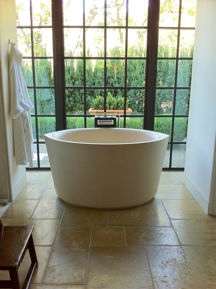 Example of a large classic master concrete floor freestanding bathtub design in San Francisco with open cabinets, black cabinets, white walls and marble countertops