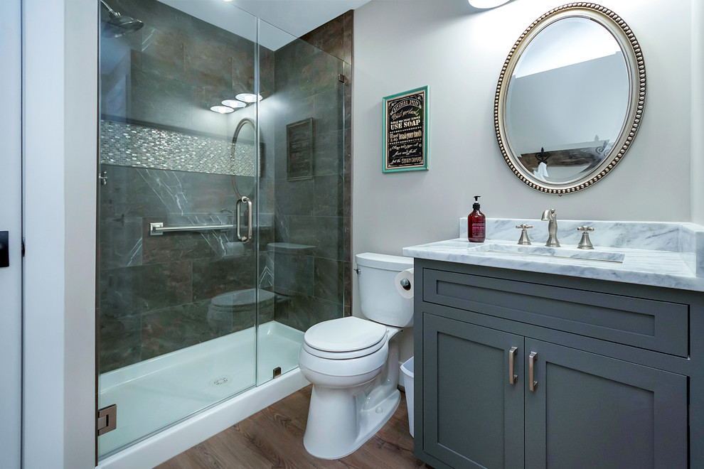Inspiration för ett mellanstort funkis badrum med dusch, med skåp i shakerstil, grå skåp, en dusch i en alkov, en toalettstol med hel cisternkåpa, brun kakel, grå väggar, mellanmörkt trägolv, ett undermonterad handfat, marmorbänkskiva, brunt golv och dusch med gångjärnsdörr