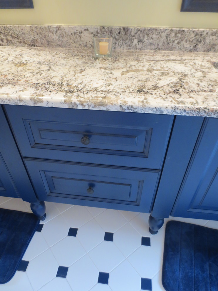 Idee per una stanza da bagno chic di medie dimensioni con ante con bugna sagomata, ante blu, pareti gialle, pavimento in gres porcellanato, lavabo sottopiano e top in granito