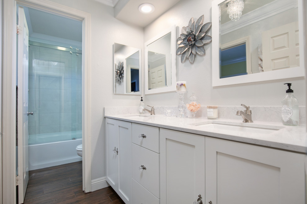 Exemple d'une petite salle de bain chic pour enfant avec un placard à porte shaker, des portes de placard blanches, une baignoire en alcôve, WC séparés, un carrelage gris, des carreaux de céramique, un mur gris, un sol en carrelage de porcelaine, un lavabo encastré, un plan de toilette en quartz modifié, un sol marron, une cabine de douche à porte coulissante et un plan de toilette gris.