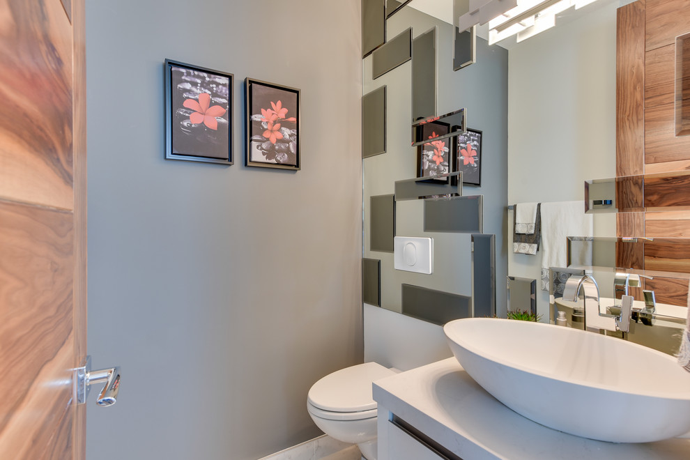 Стильный дизайн: ванная комната среднего размера в современном стиле с плоскими фасадами, белыми фасадами, ванной в нише, душем над ванной, унитазом-моноблоком, серой плиткой, зеркальной плиткой, серыми стенами, паркетным полом среднего тона, душевой кабиной, настольной раковиной и столешницей из искусственного кварца - последний тренд