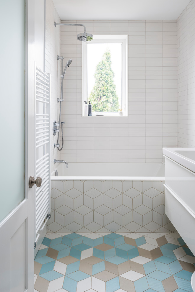 Bild på ett litet funkis vit vitt badrum med dusch, med släta luckor, vita skåp, vit kakel, tunnelbanekakel, vita väggar, klinkergolv i keramik, med dusch som är öppen, ett badkar i en alkov, en dusch/badkar-kombination, ett konsol handfat och flerfärgat golv
