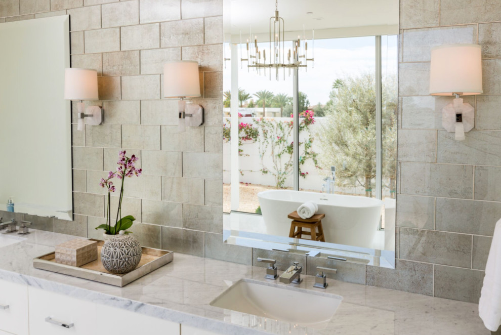 Bild på ett stort funkis en-suite badrum, med släta luckor, vita skåp, ett fristående badkar, beige kakel, stenkakel, beige väggar, ett undermonterad handfat och bänkskiva i kvarts