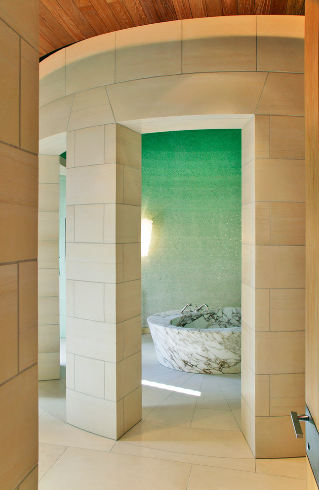 Aménagement d'une salle de bain contemporaine avec une baignoire indépendante, un carrelage beige et un mur vert.