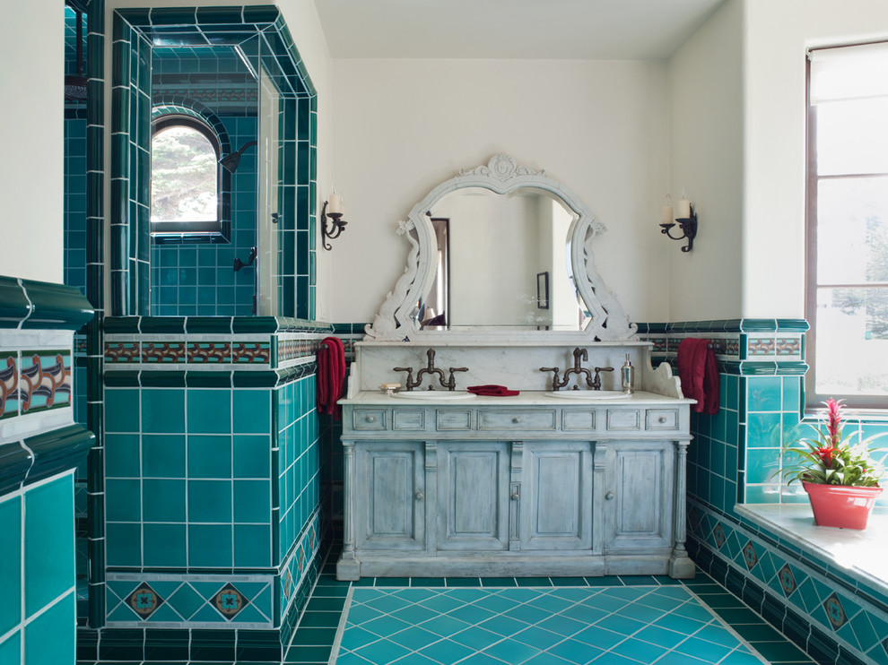 На фото: ванная комната в средиземноморском стиле с накладной раковиной, серыми фасадами, синей плиткой, белыми стенами, бирюзовым полом и фасадами с выступающей филенкой с