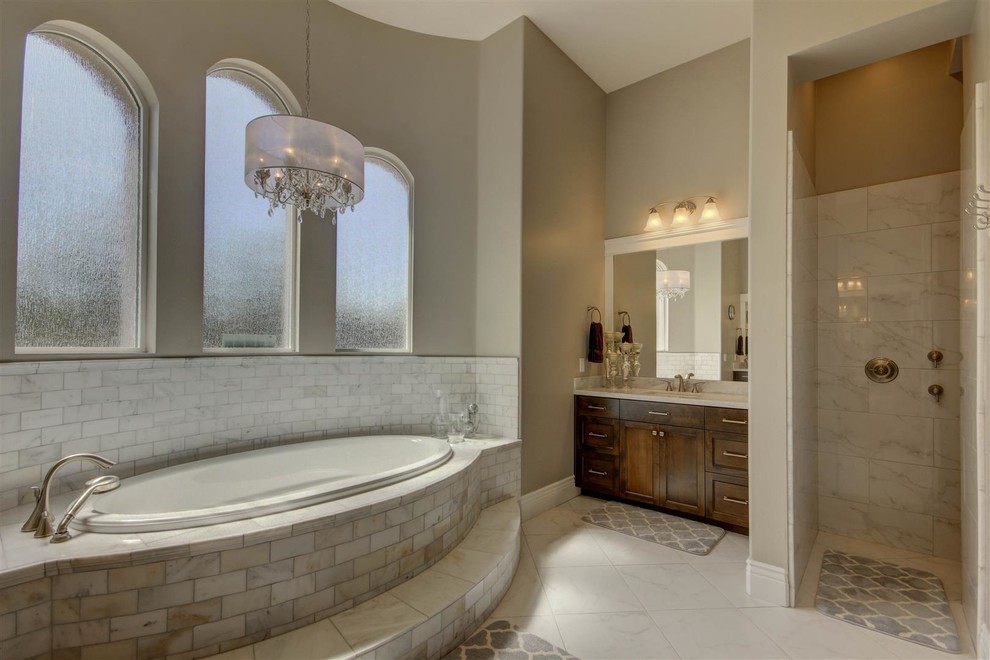 Example of a large transitional master gray tile, white tile and stone tile marble floor drop-in bathtub design in Phoenix with recessed-panel cabinets, dark wood cabinets, gray walls, an undermount sink and marble countertops