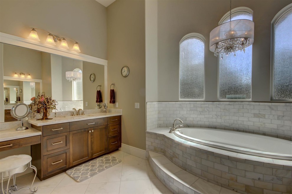 Large elegant master gray tile, white tile and stone tile marble floor drop-in bathtub photo in Phoenix with recessed-panel cabinets, dark wood cabinets, gray walls, an undermount sink and marble countertops