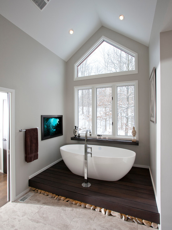 Foto de cuarto de baño principal de estilo zen de tamaño medio con bañera exenta, paredes grises y suelo de madera oscura