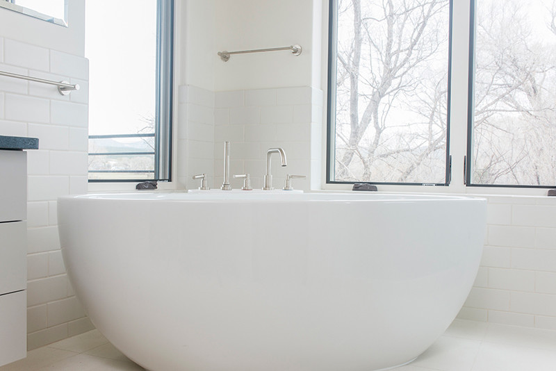 На фото: большая главная ванная комната в современном стиле с плоскими фасадами, белыми фасадами, отдельно стоящей ванной, душем в нише, белой плиткой, плиткой кабанчик, белыми стенами, полом из керамогранита, настольной раковиной и столешницей из искусственного камня с
