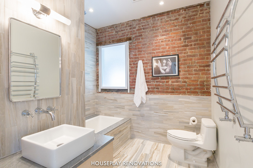 Inspiration pour une salle de bain principale minimaliste en bois clair de taille moyenne avec une baignoire posée, une douche d'angle, un placard à porte plane, WC à poser, un carrelage gris et un mur beige.