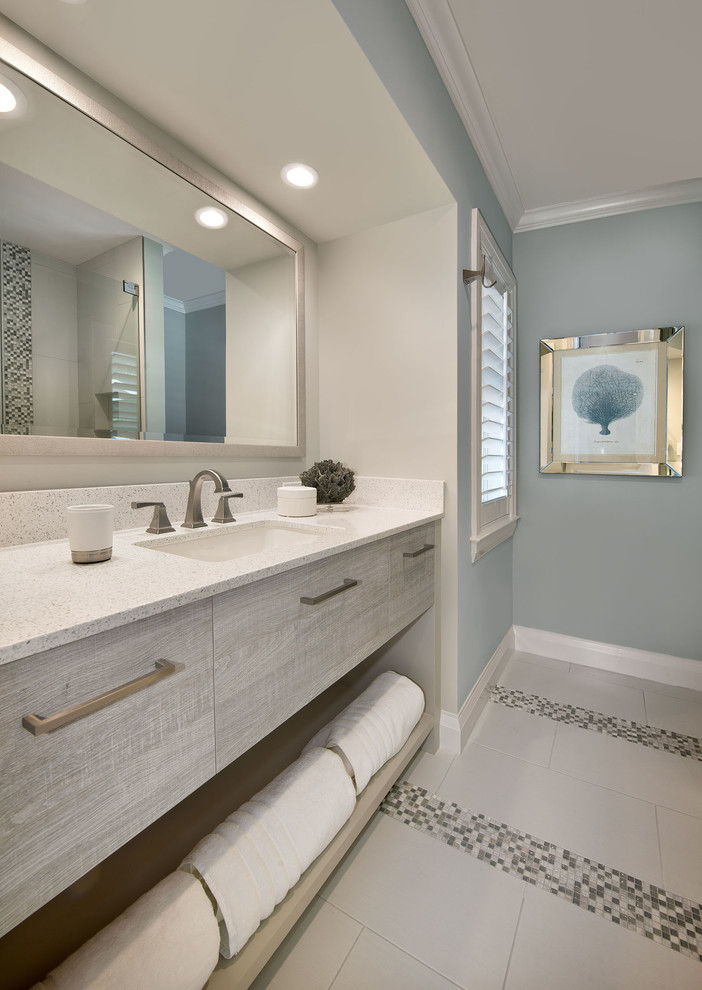 Diseño de cuarto de baño principal, marinero, de tamaño medio, con armarios con paneles lisos, puertas de armario de madera clara, paredes azules, lavabo bajoencimera, encimera de laminado y suelo de baldosas de cerámica