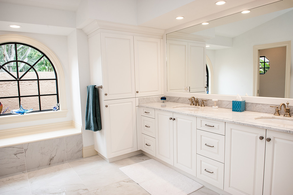 This is an example of a medium sized traditional ensuite bathroom in Miami with shaker cabinets, white cabinets, a built-in bath, a corner shower, a one-piece toilet, white walls, a submerged sink, marble worktops and a hinged door.