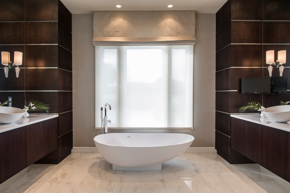 Cette photo montre une grande salle de bain tendance en bois foncé avec une vasque, un placard à porte plane, une baignoire indépendante et un mur beige.