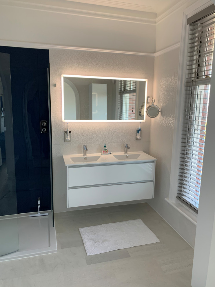 Inspiration for a medium sized contemporary family bathroom in Sussex with flat-panel cabinets, white cabinets, a freestanding bath, a corner shower, a two-piece toilet, blue tiles, pebble tiles, white walls, vinyl flooring, an integrated sink, grey floors, a sliding door, white worktops, an enclosed toilet, a single sink and a floating vanity unit.