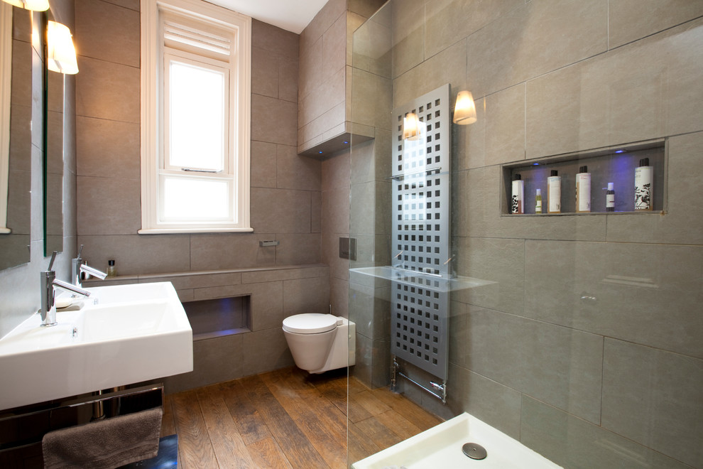 Design ideas for a medium sized contemporary ensuite bathroom in London with a wall-mounted sink, flat-panel cabinets, a wall mounted toilet, grey tiles, stone slabs, grey walls and medium hardwood flooring.