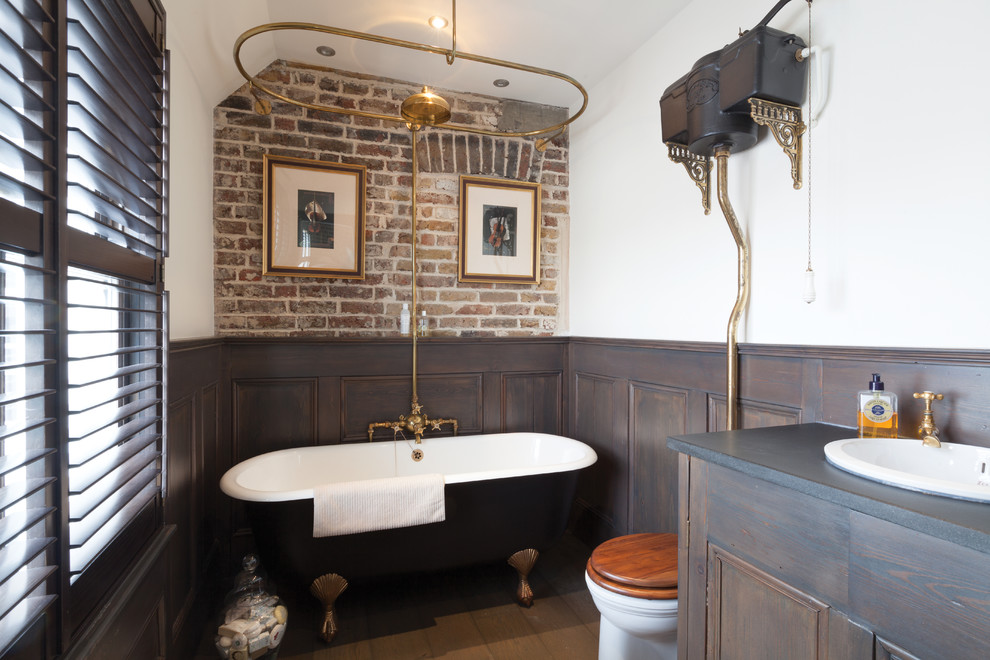 Idéer för vintage en-suite badrum, med luckor med infälld panel, skåp i mörkt trä, ett badkar med tassar, en dusch/badkar-kombination, en toalettstol med separat cisternkåpa, vita väggar, mellanmörkt trägolv, ett nedsänkt handfat, träbänkskiva, brunt golv och med dusch som är öppen