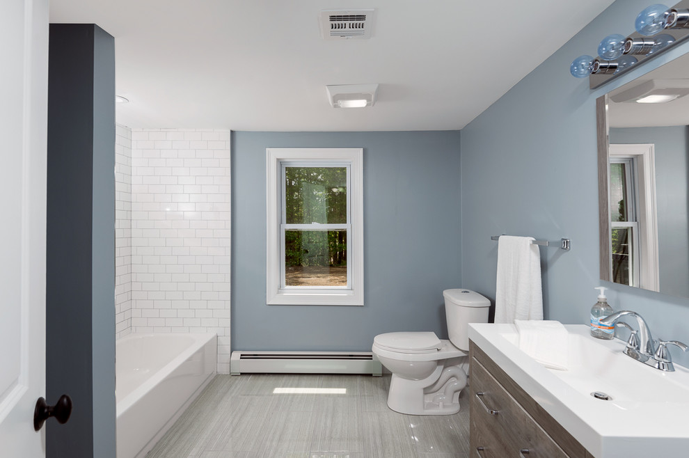 Exempel på ett litet klassiskt en-suite badrum, med släta luckor, skåp i mörkt trä, ett platsbyggt badkar, en dusch/badkar-kombination, en toalettstol med separat cisternkåpa, vit kakel, tunnelbanekakel, blå väggar, klinkergolv i keramik, ett nedsänkt handfat, laminatbänkskiva, dusch med duschdraperi och grått golv
