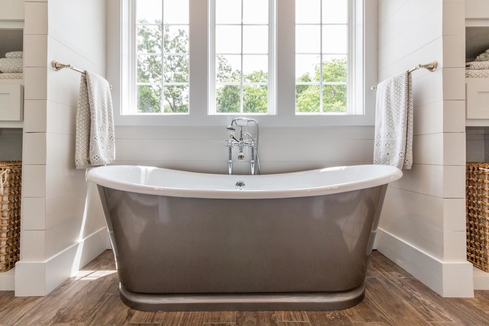 Inspiration for a large transitional master medium tone wood floor and brown floor freestanding bathtub remodel in Tampa with shaker cabinets, white cabinets and white walls