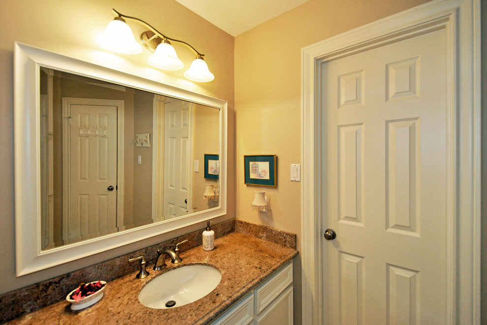 Foto di una stanza da bagno con doccia tradizionale di medie dimensioni con lavabo sottopiano, ante con riquadro incassato, ante bianche, piastrelle beige e pareti gialle