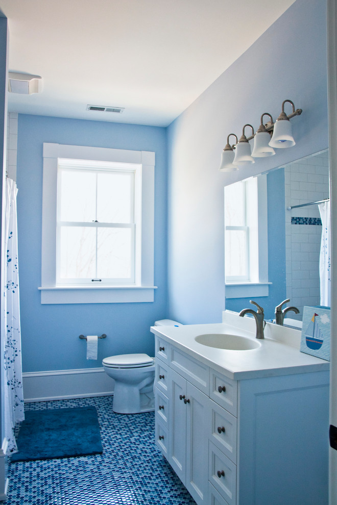 На фото: ванная комната среднего размера в классическом стиле с фасадами с утопленной филенкой, белыми фасадами, угловой ванной, душем над ванной, раздельным унитазом, синими стенами, полом из галечной плитки, душевой кабиной, врезной раковиной и столешницей из искусственного камня