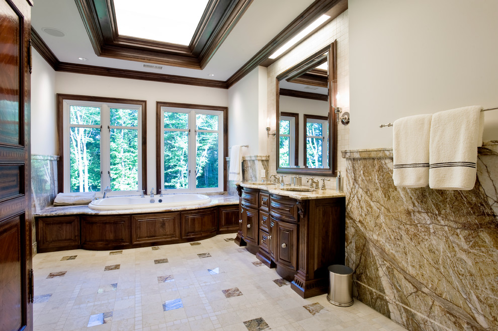 Réalisation d'une salle de bain tradition en bois foncé avec un lavabo encastré, un placard avec porte à panneau surélevé et une baignoire posée.