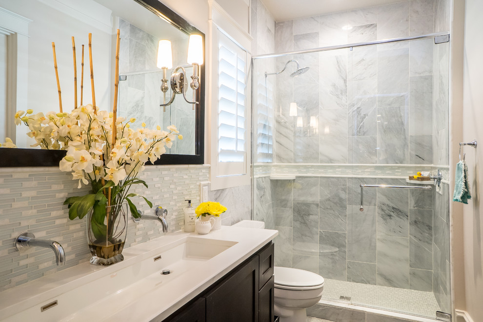 Cette photo montre une salle de bain chic avec un placard avec porte à panneau encastré, des portes de placard noires, WC séparés, un carrelage gris, un carrelage blanc, du carrelage en marbre, un mur gris, une grande vasque et une cabine de douche à porte battante.