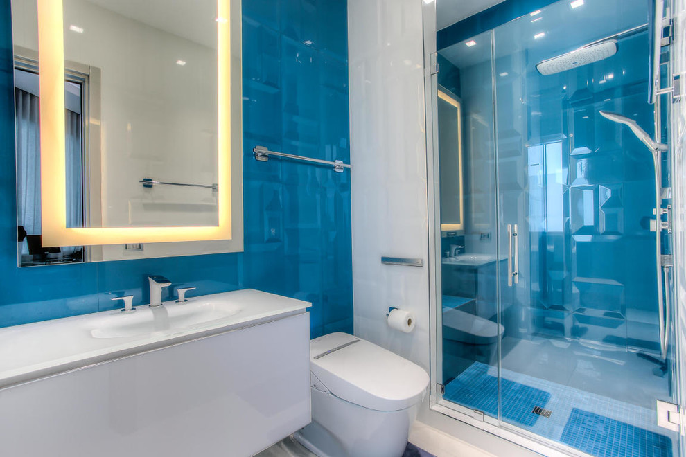 Diseño de cuarto de baño contemporáneo de tamaño medio con armarios con paneles lisos, puertas de armario blancas, ducha empotrada, bidé, baldosas y/o azulejos azules, baldosas y/o azulejos de porcelana, paredes azules, suelo de baldosas de porcelana, aseo y ducha, lavabo integrado y encimera de vidrio