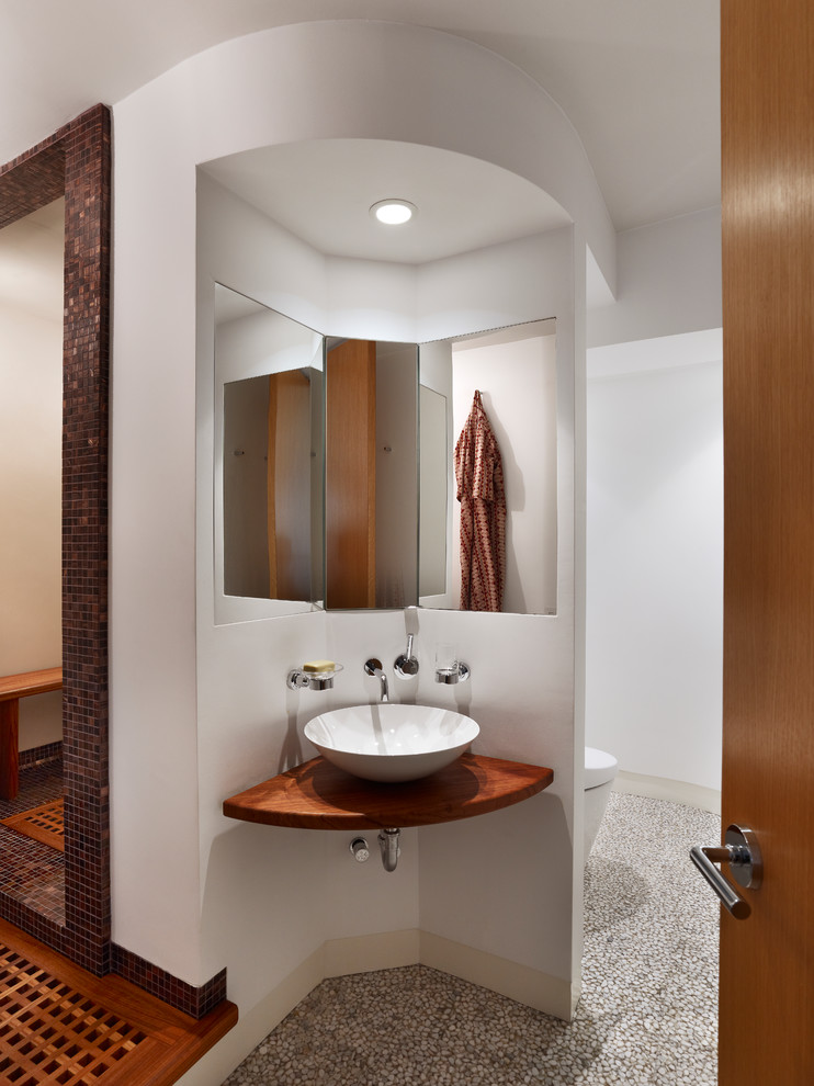 Diseño de cuarto de baño principal contemporáneo con lavabo sobreencimera, encimera de madera, baldosas y/o azulejos marrones y paredes blancas