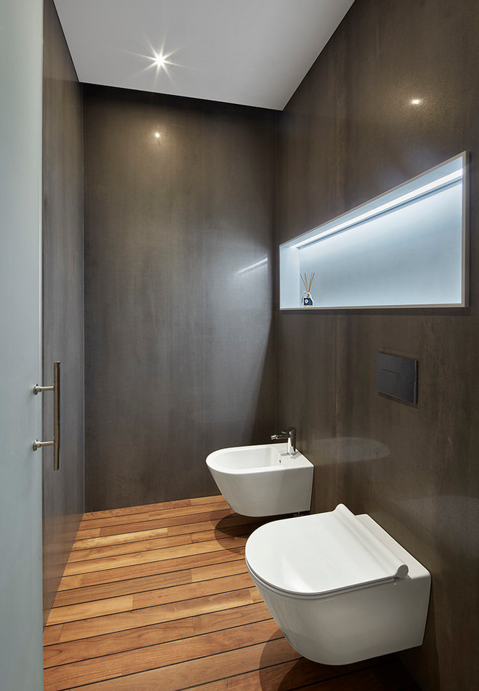 Immagine di una stanza da bagno minimalista con bidè, pareti grigie, pavimento in legno massello medio e pavimento marrone