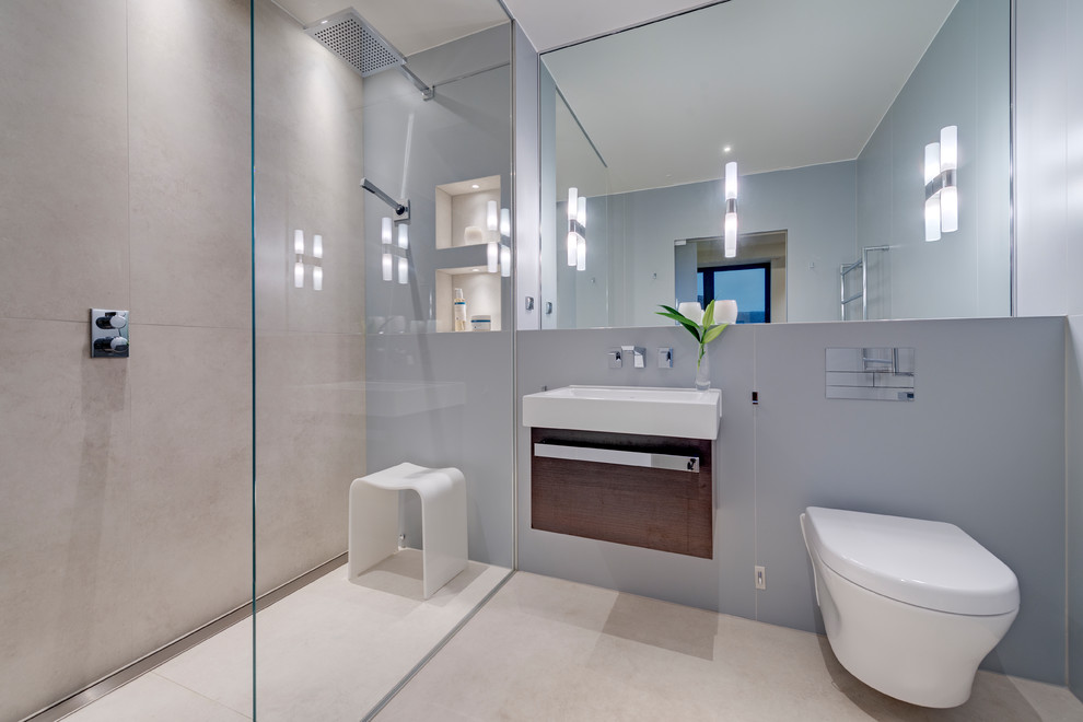 This is an example of a medium sized contemporary ensuite bathroom in Devon with freestanding cabinets, dark wood cabinets, a walk-in shower, a wall mounted toilet, beige tiles, porcelain tiles, beige walls, porcelain flooring, a wall-mounted sink, beige floors and an open shower.
